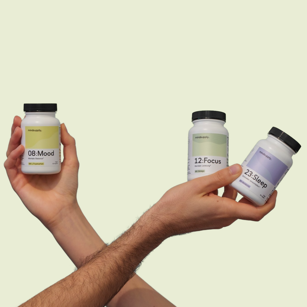 Nahrungsergänzungsmittel Mindsupply Dosen werden in Händen gehalten mit grünem Hintergrund